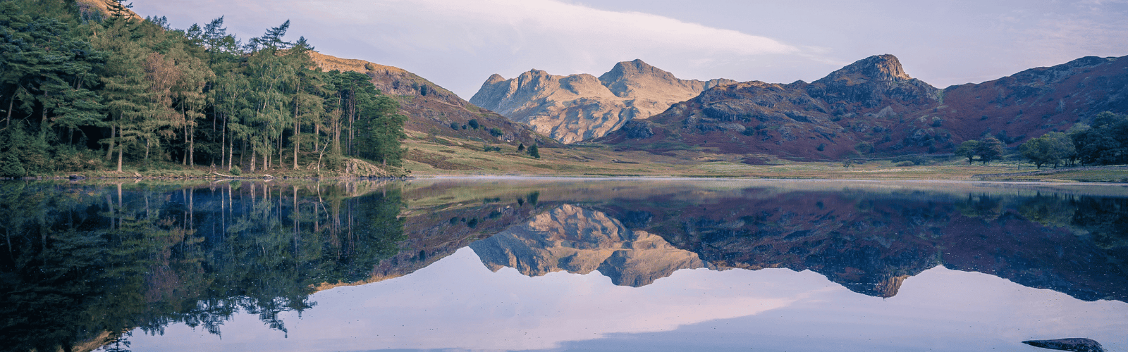 Un lac avec des arbres et de montagnes qui se reflètent dedans
